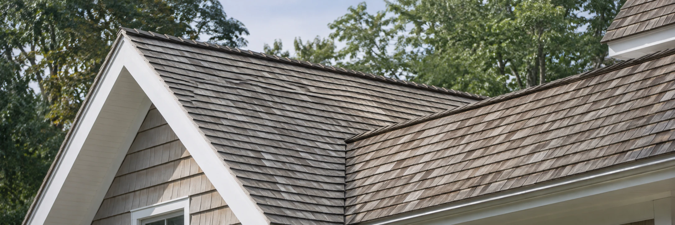 Weathered cedar shingle roof with multiple gables and crisp white trim.