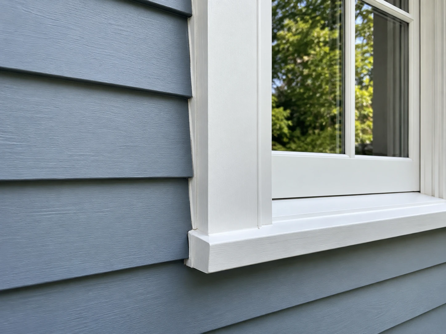 Close-up of blue-gray clapboard siding with crisp white window trim.
